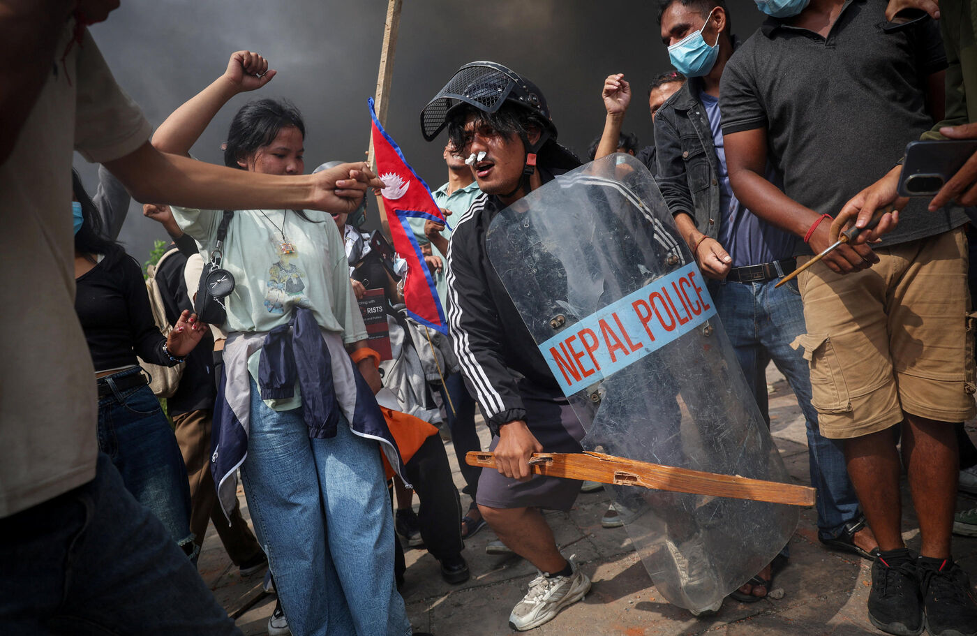 Demonstrators celebrate as smoke rises from a fire set at the Parliament complex during a protest against Monday's killing of 19 people after anti-corruption protests that were triggered by a social media ban, which was later lifted, during a curfew in Kathmandu, Nepal, September 9, 2025. REUTERS/Adnan Abidi